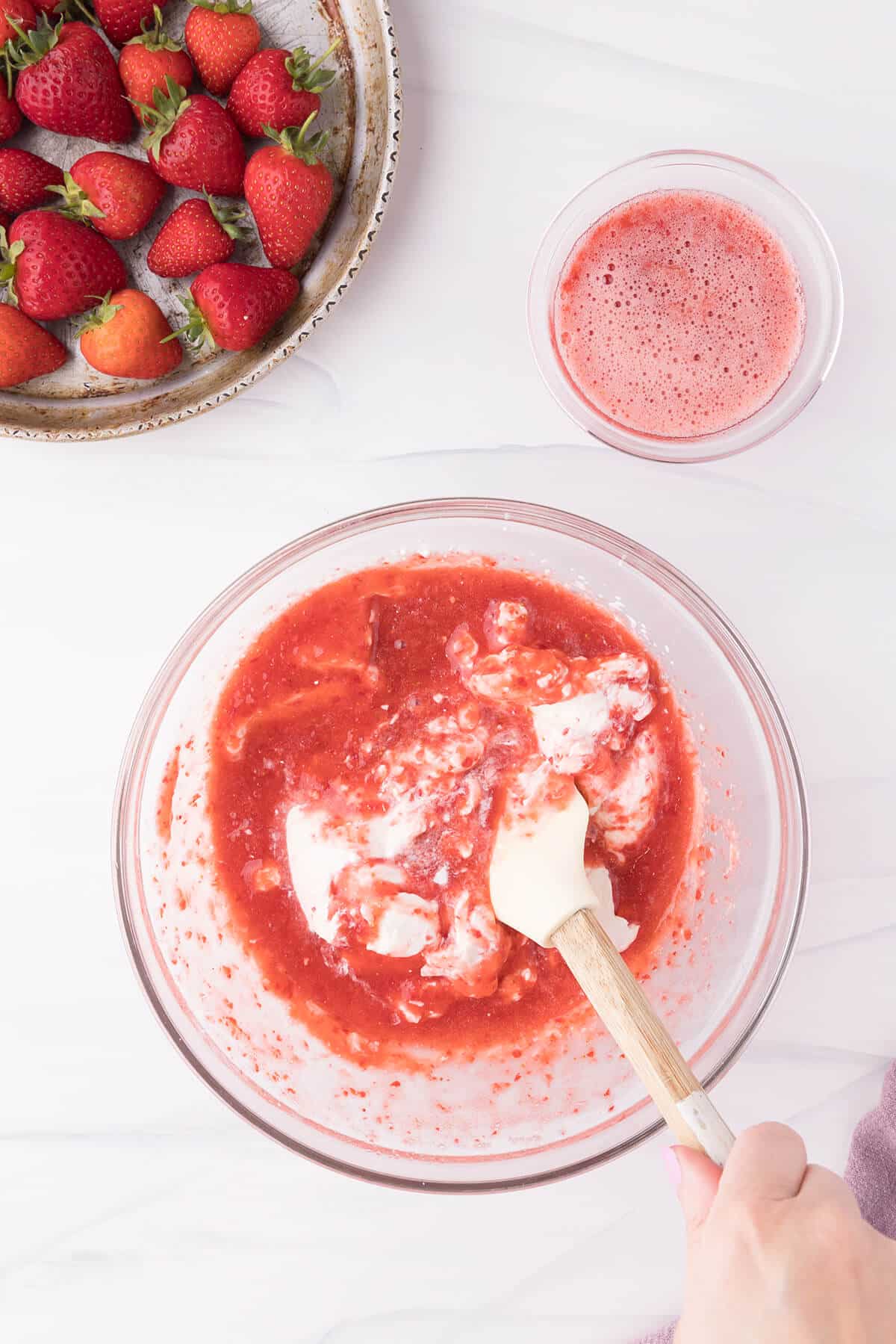 combining fresh strawberry puree to the heavy whipped cream.