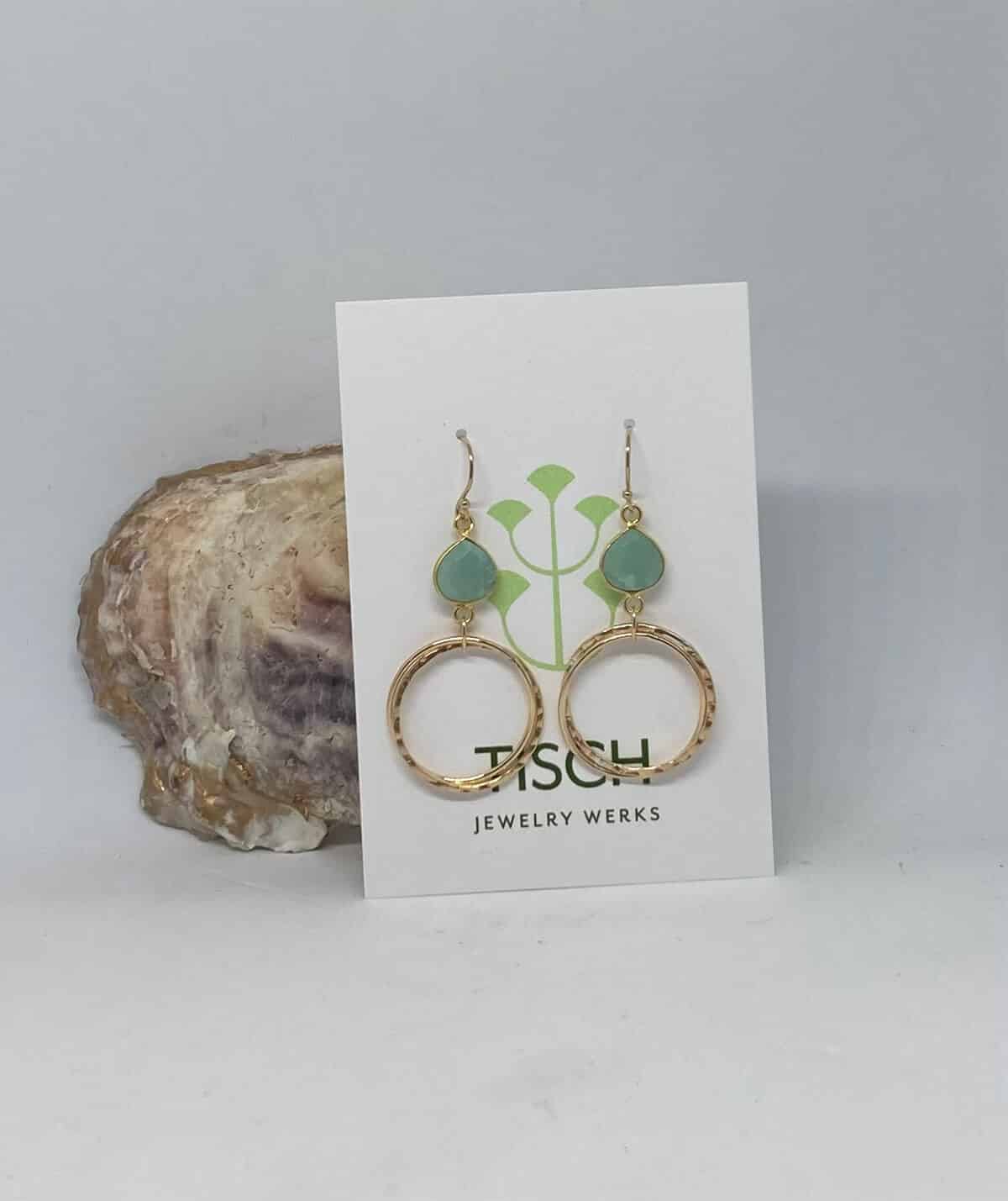 Earrings with a blue stone and gold hoops on a white card.