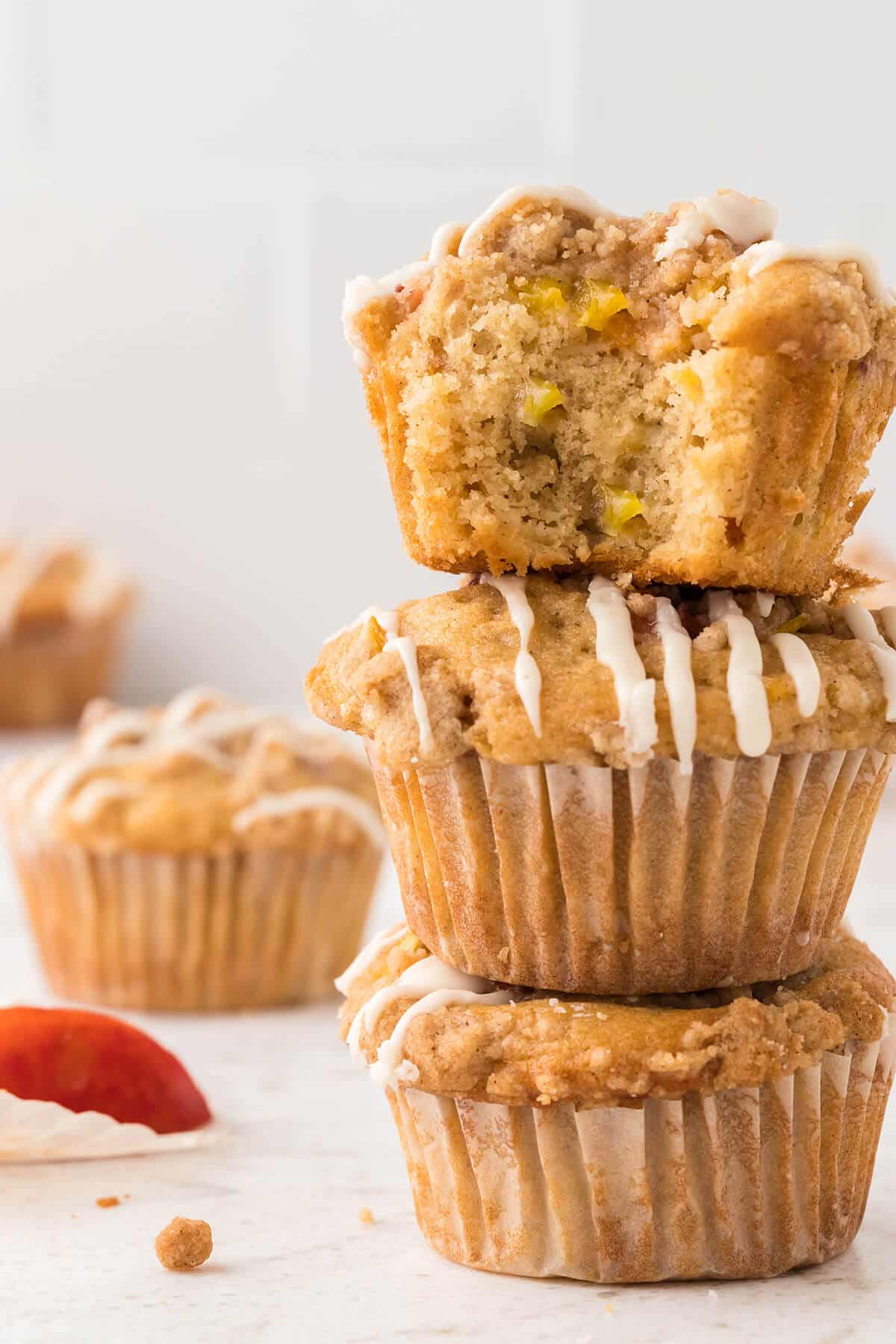 stack of peach muffins with one having a bite taken out of it 