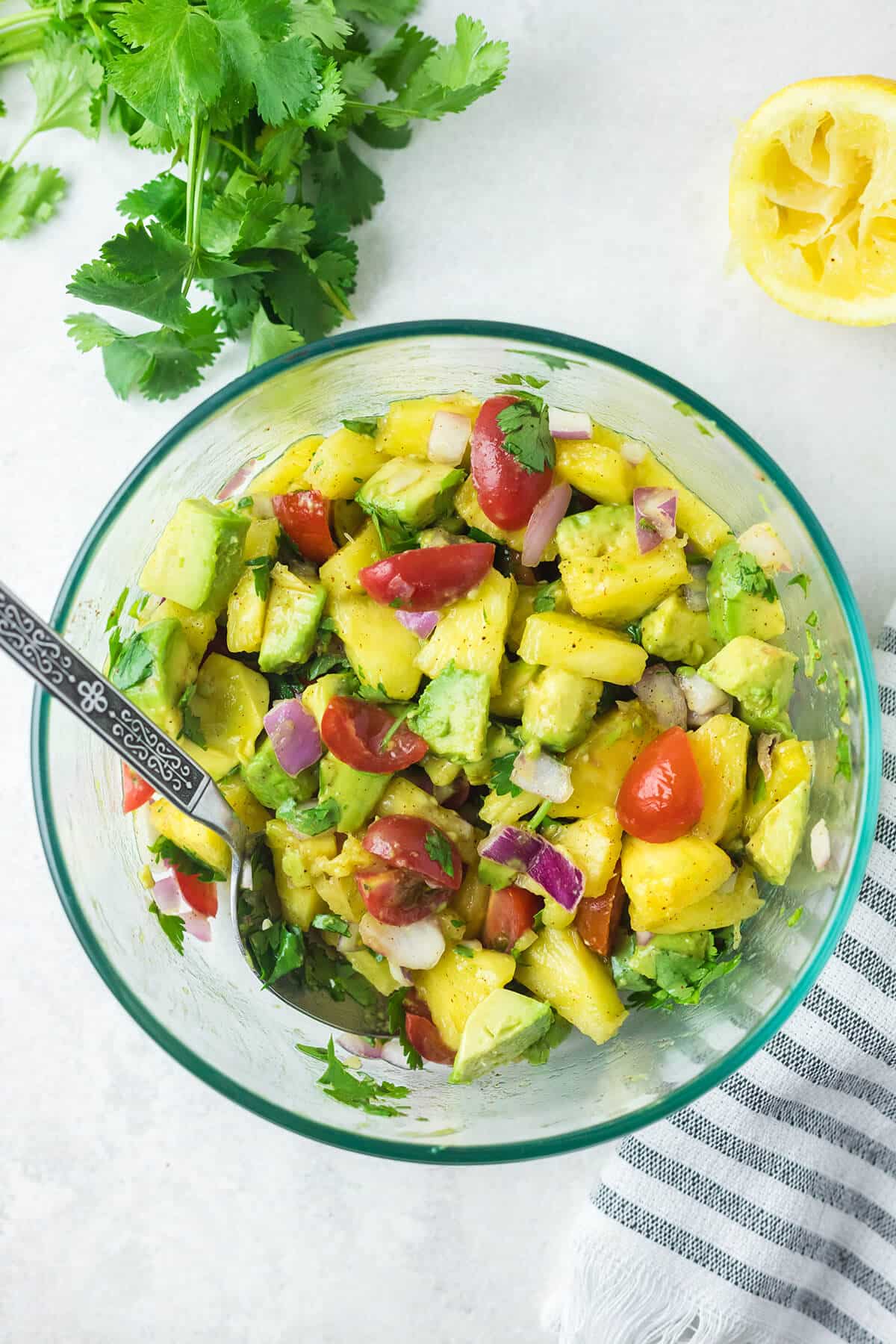 spoon stirring pineapple salsa in a bowl.