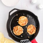cast iron skillet with salmon patties and a spatula