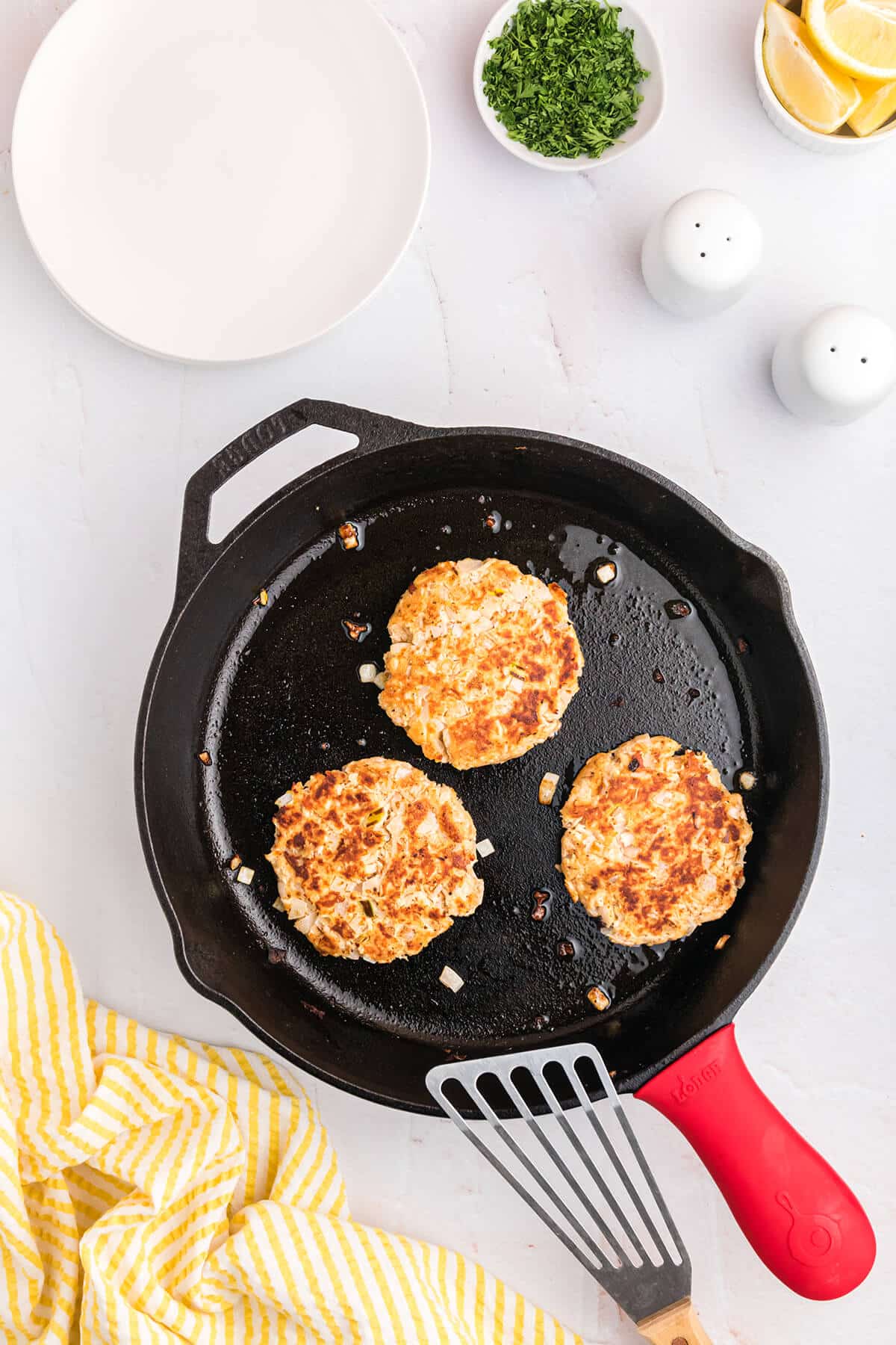 cast iron skillet with salmon patties and a spatula