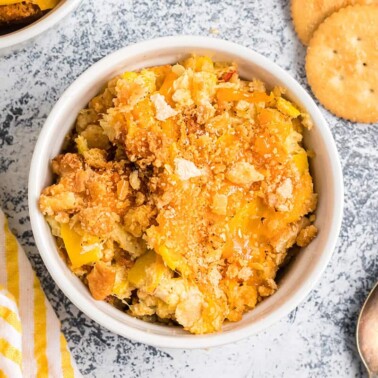 Overhead closeup of baked yellow squash casserole in a white dish.