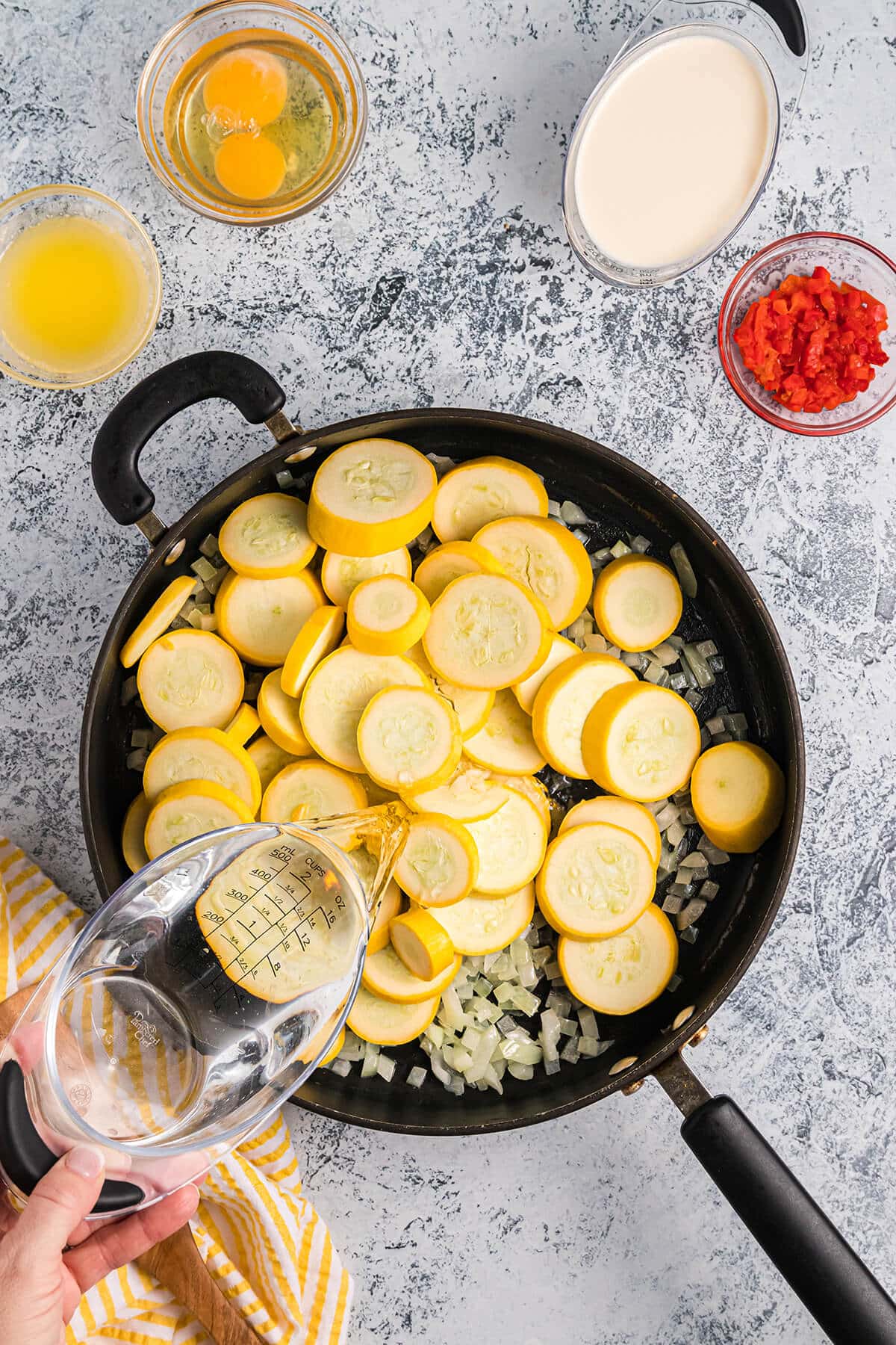 Sliced yellow squash and onion in a skillet.