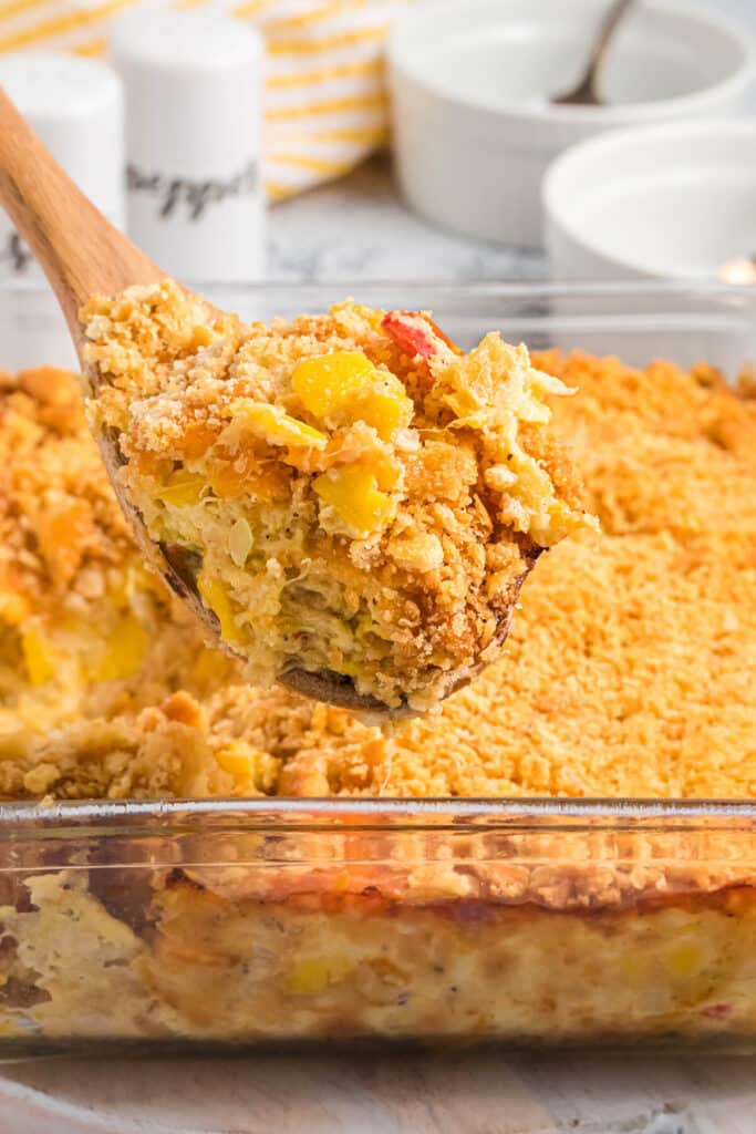 Closeup of a spoon of squash casserole held over the baking dish.