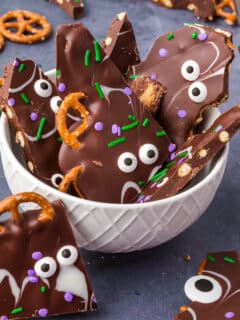 a white bowl filled with pretzel bark with green and purple sprinkles for halloween