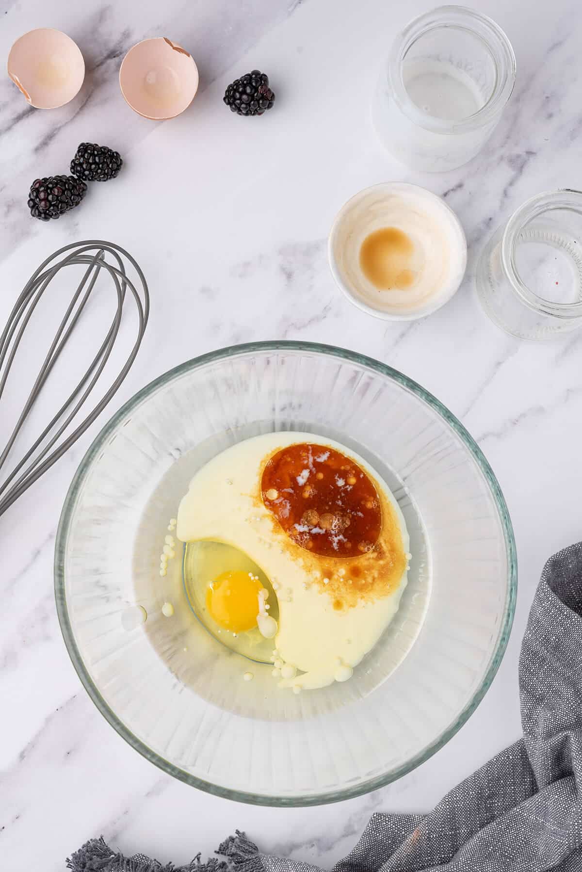 Egg and buttermilk combined in a clear glass bowl.