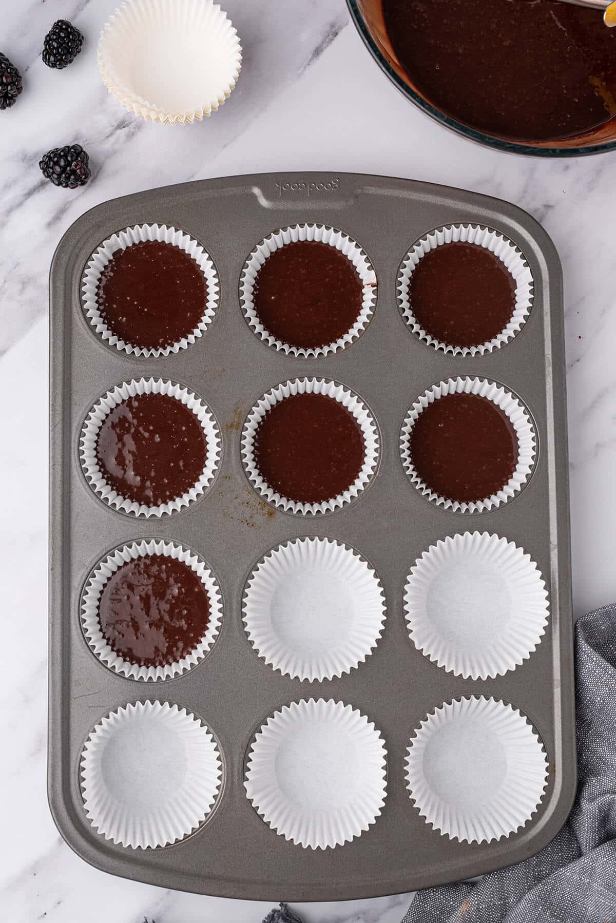 Chocolate cupcake batter in muffin liners in a muffin pan.