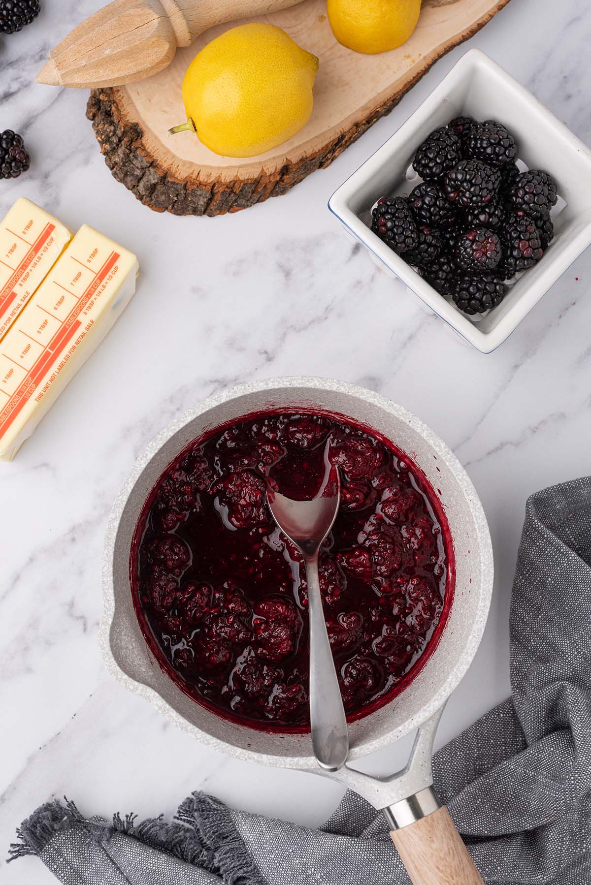 Mashed blackberries in a white bowl with a spoon.