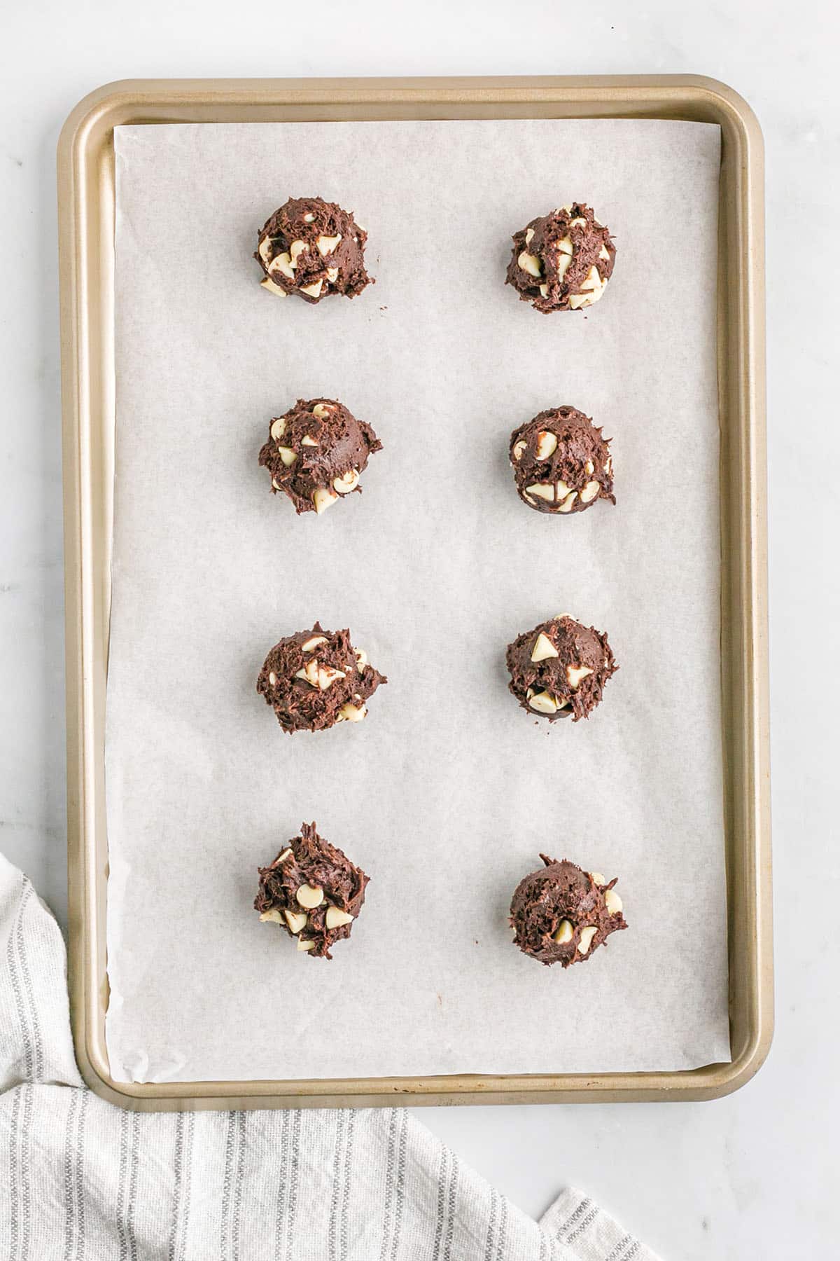 Balls of chocolate cake mix cookie dough on a baking sheet.