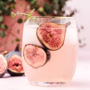 A glass filled with a cocktail with fresh fig slices.