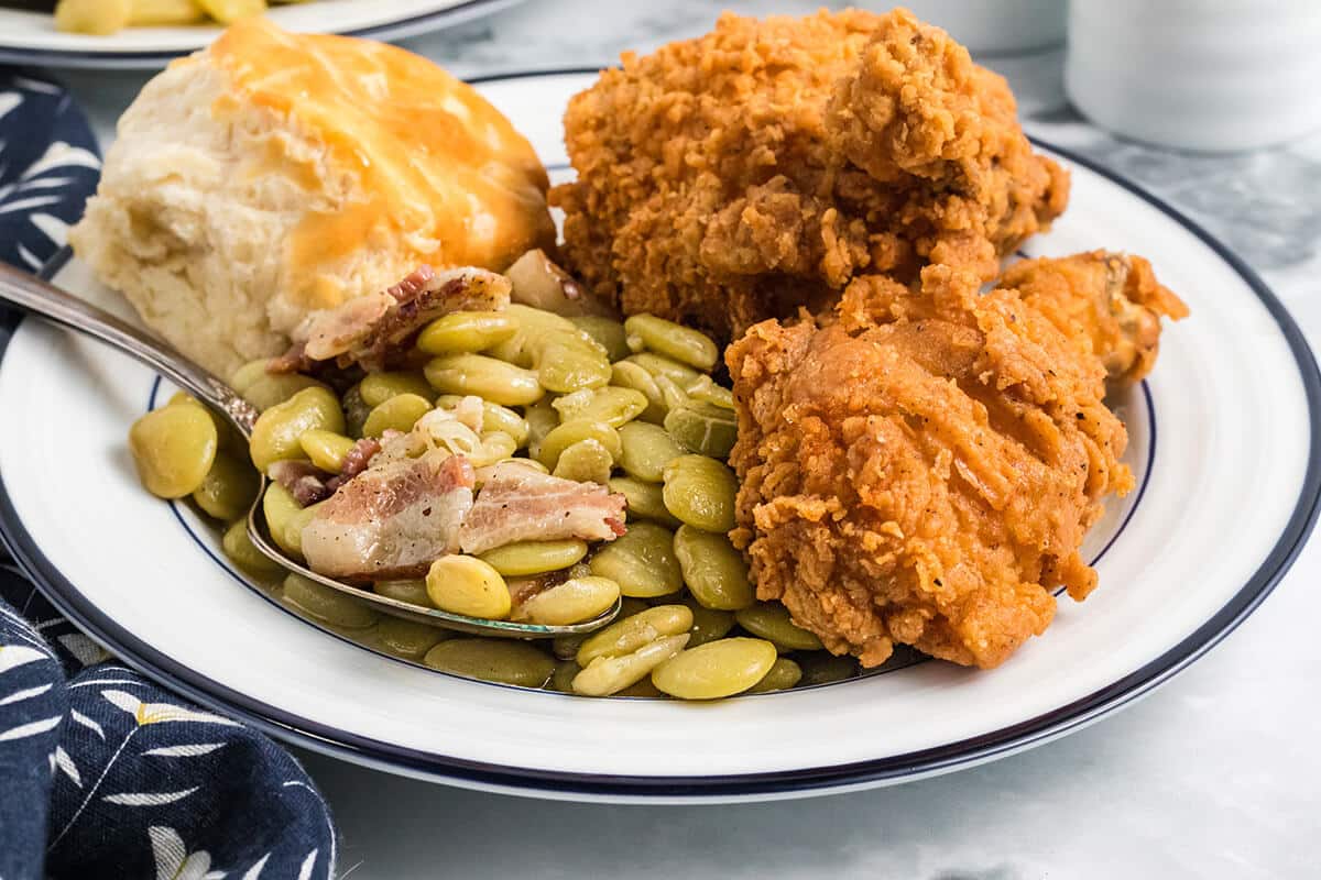 Plate with fried chicken, butter beans, and biscuit.