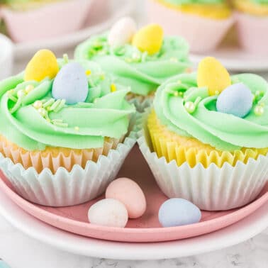 Three Easter cupcakes on a plate with mini eggs.