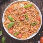 Heirloom tomato pasta in a bowl topped with pangrattato and basil.