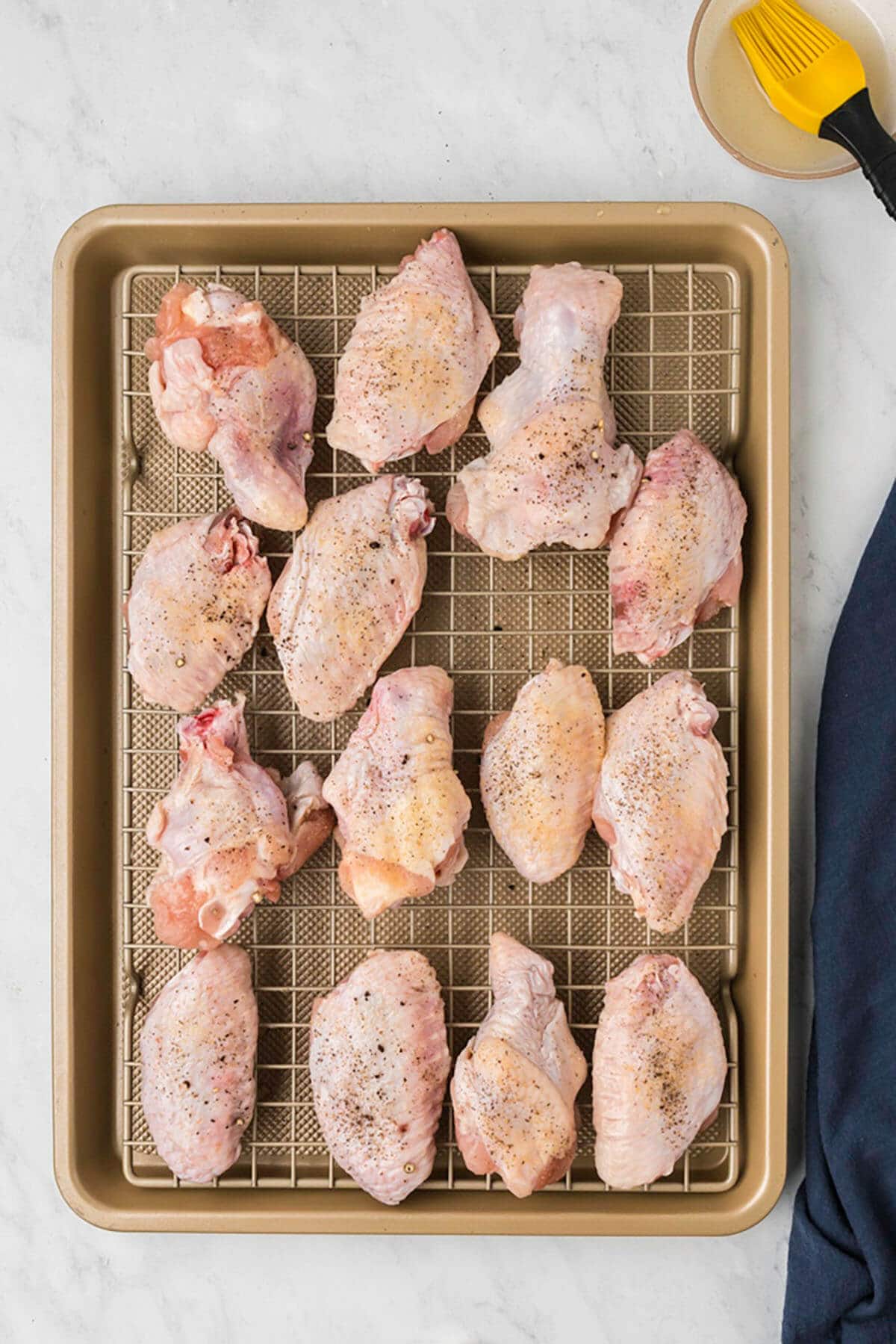 Raw chicken wings on a pan to cook. 