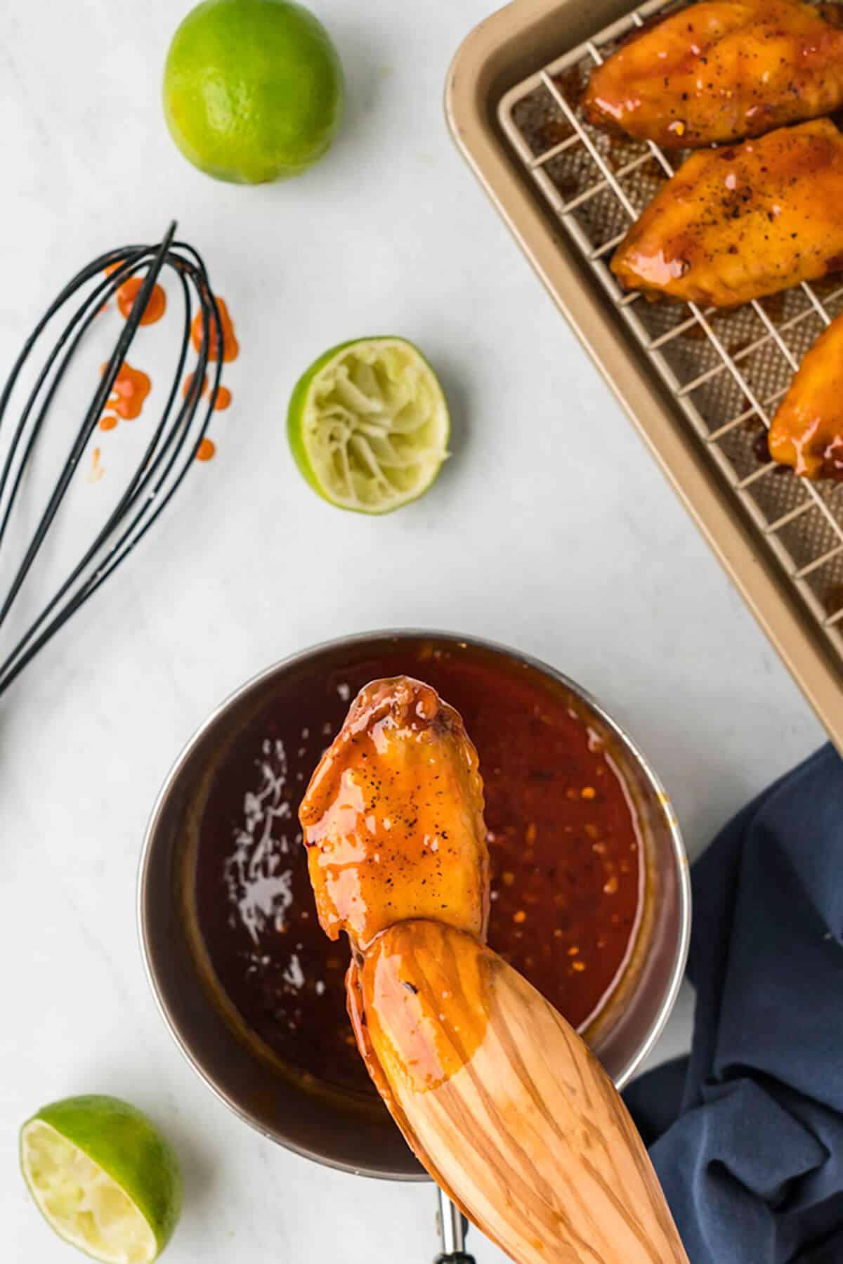 Dipping wings into sauce.