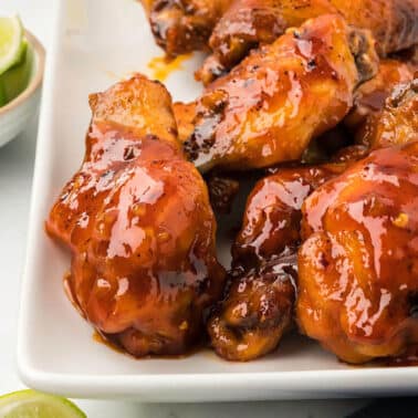 Spicy honey garlic wings on a white platter.