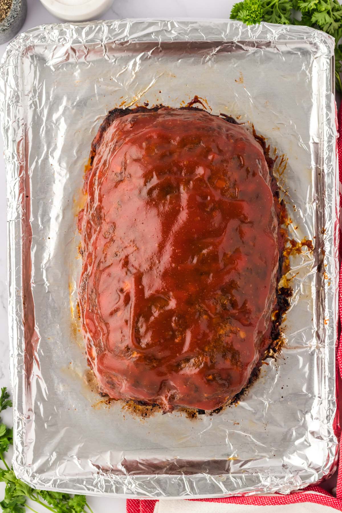 Meatloaf covered with brown sugar glaze on a baking sheet.