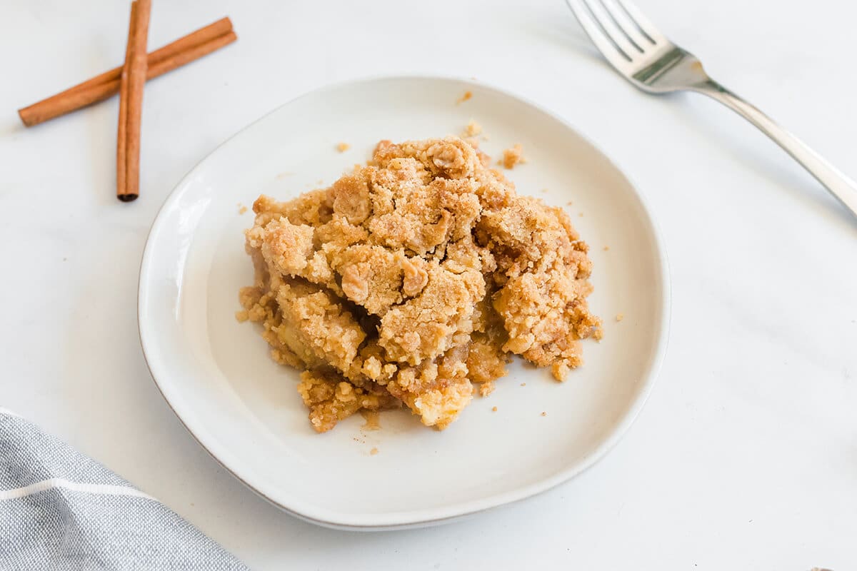 Serving of apple crisp without oats on a white plate.