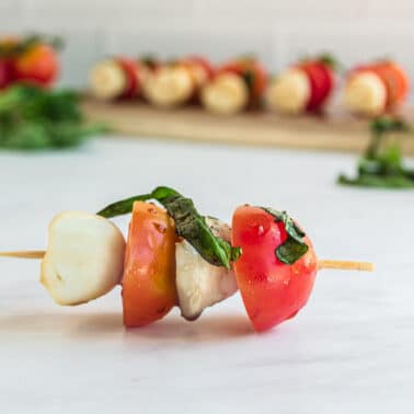 tomatoes and mozzarella on a stick with basil.