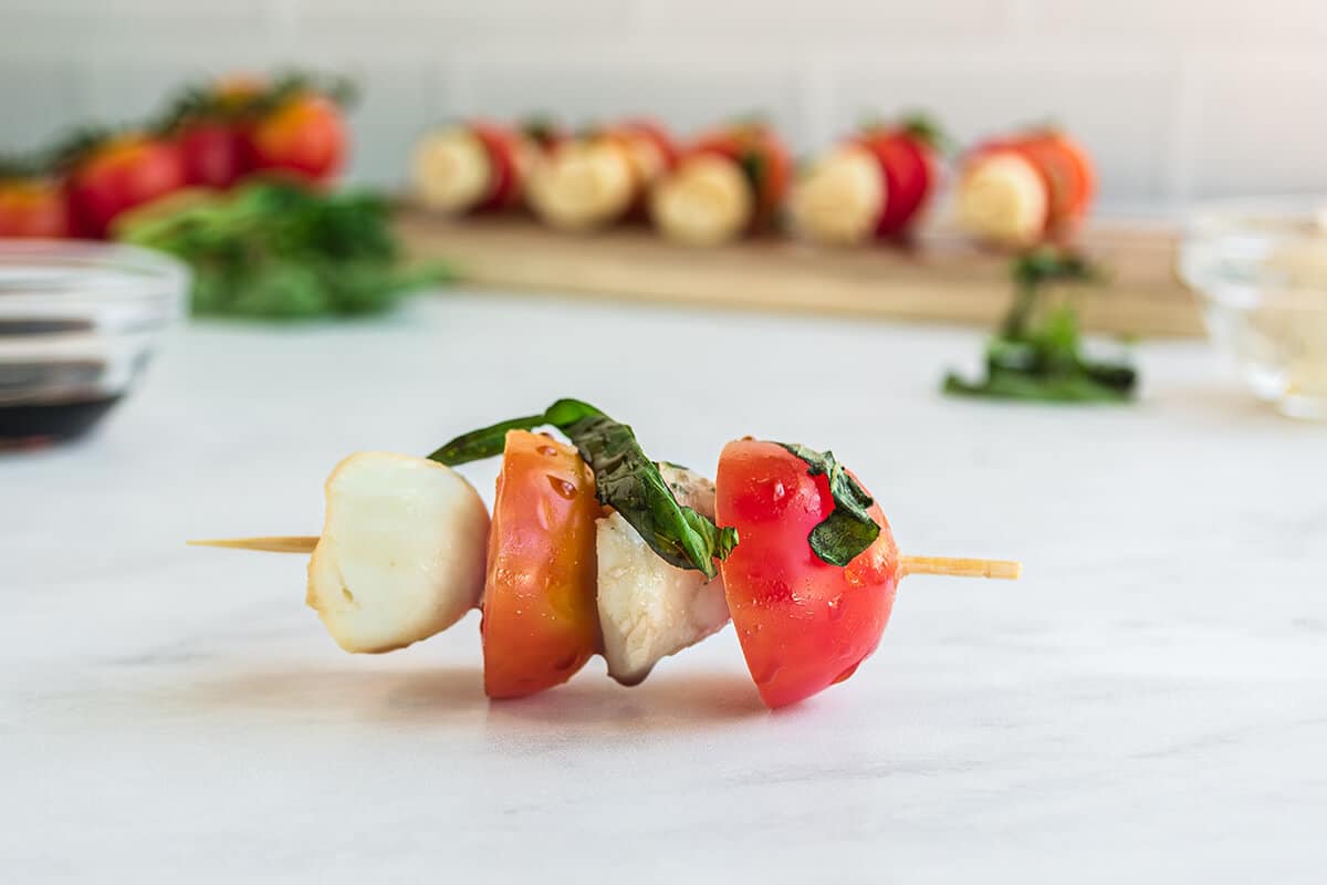 tomatoes and mozzarella on a stick with basil.