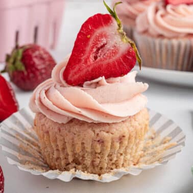 Strawberry buttercream on a cupcake with a fresh strawberry.