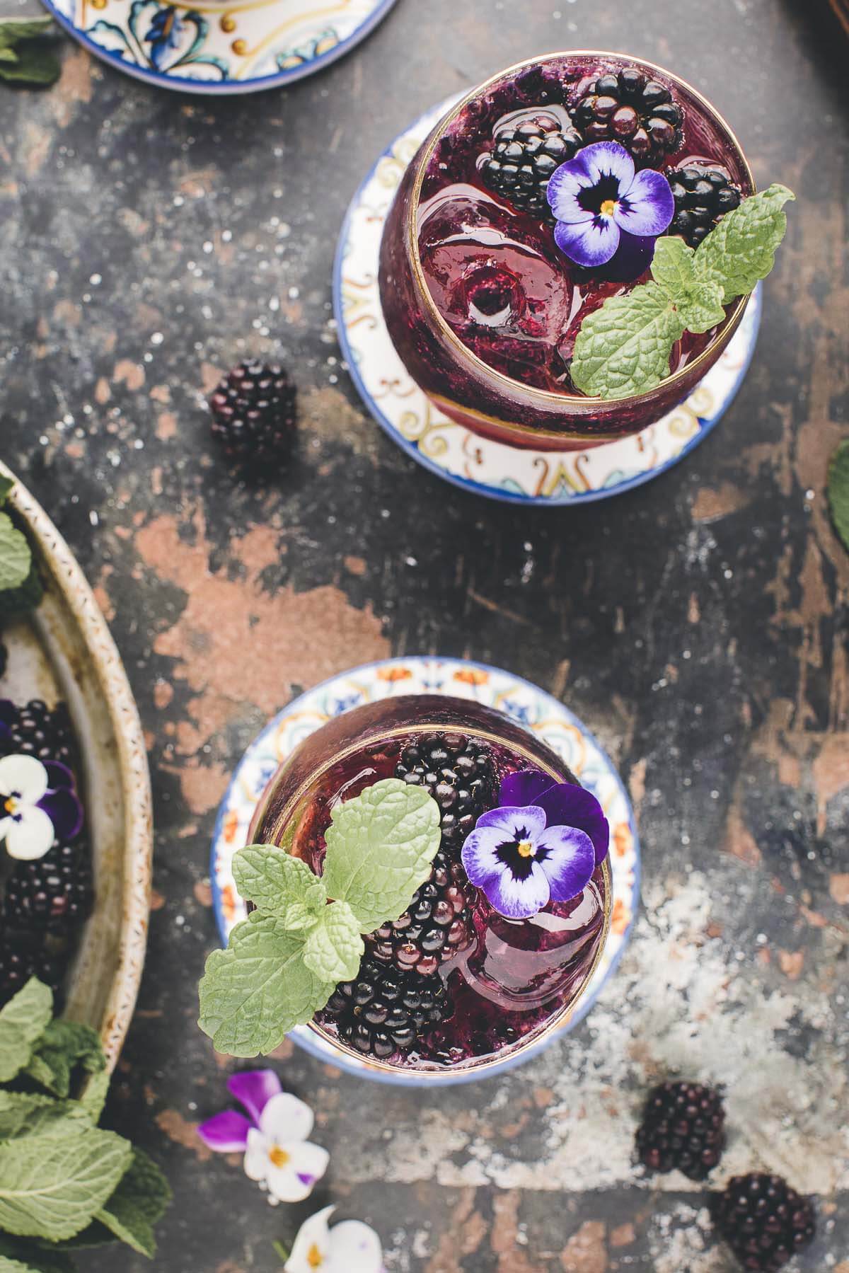 Blackberry mojito garnished with mint on a dark board.