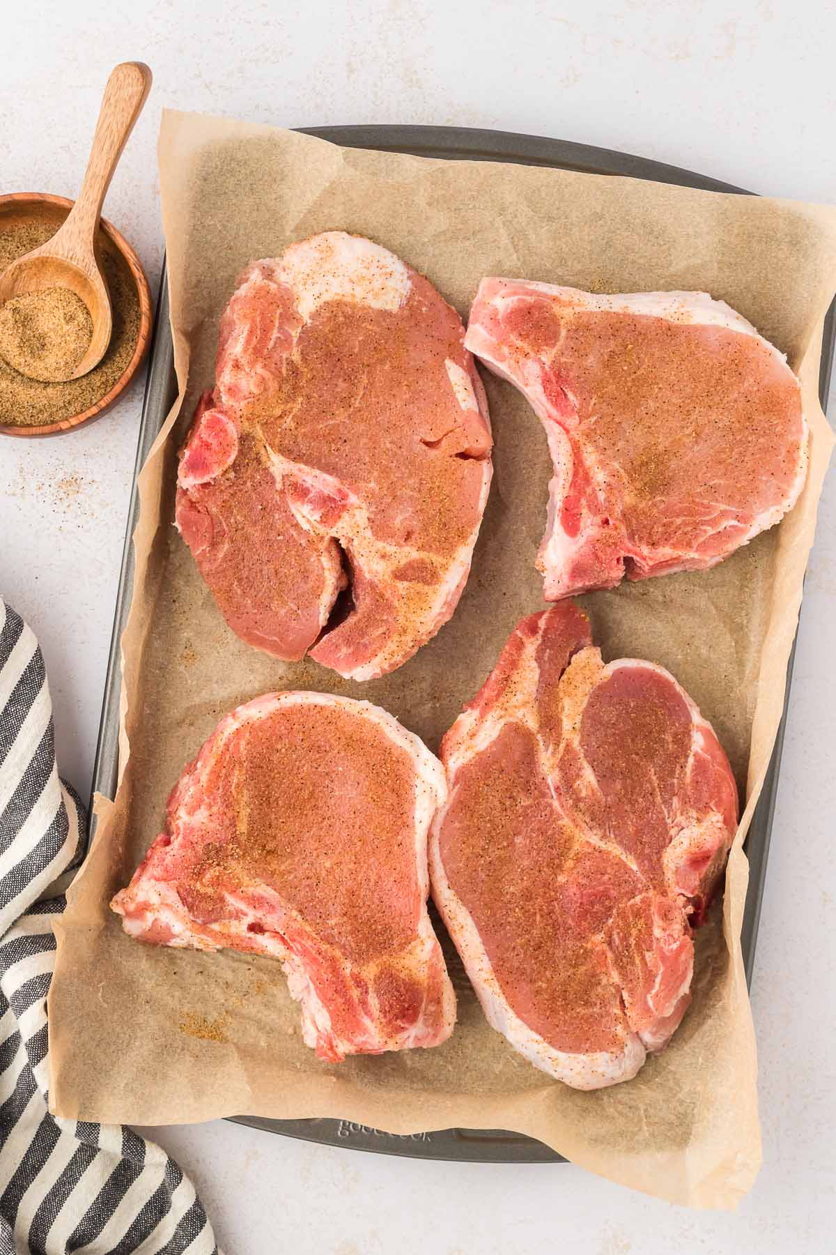 Pork chops on a board with seasoning.
