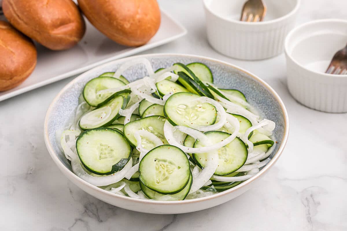 Large white bowl of cucumber onion salad.