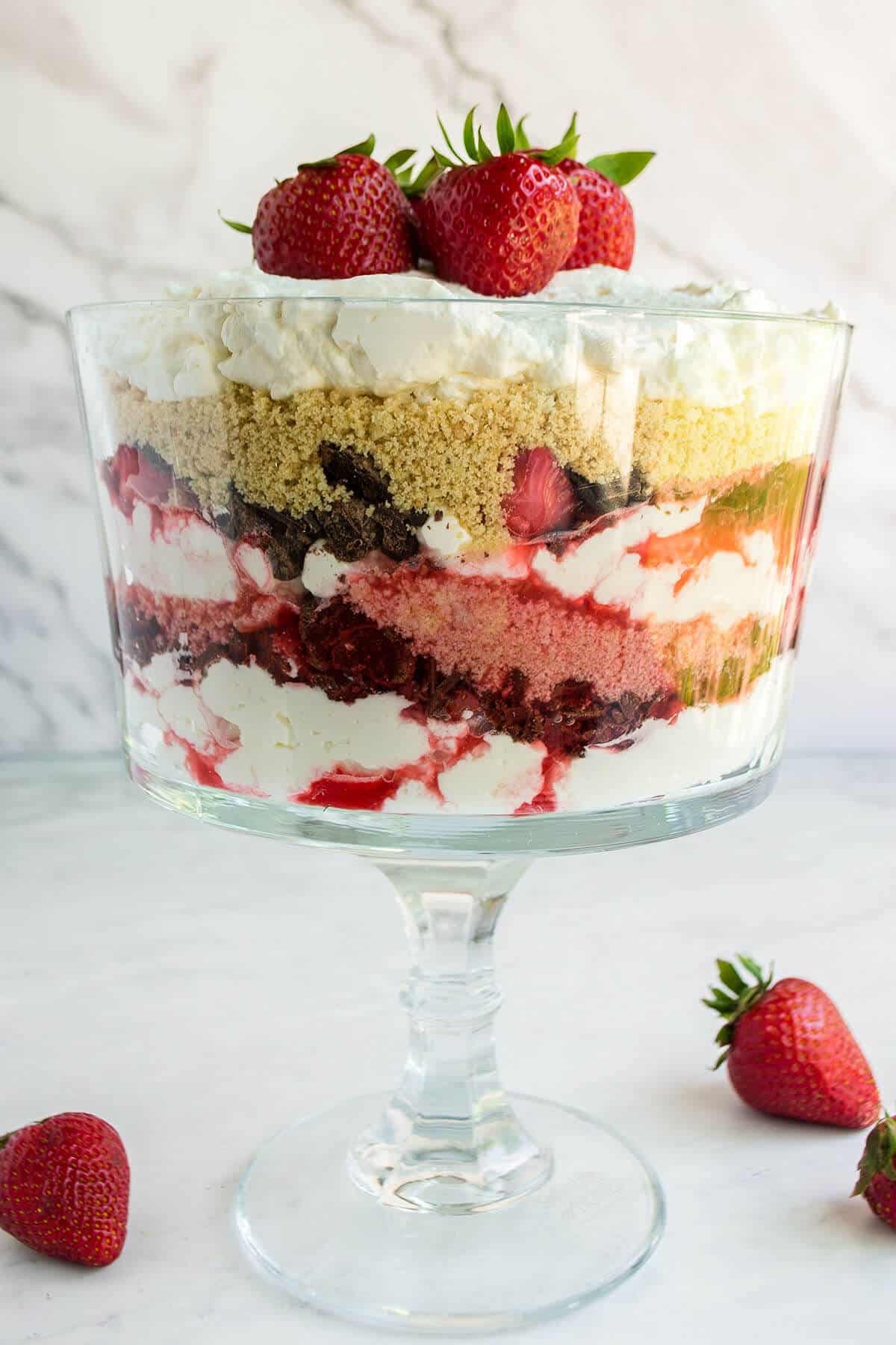 glass trifle bowl filled with layers of strawberry and whipped cream.