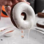 A donut dipped in a bowl of icing.