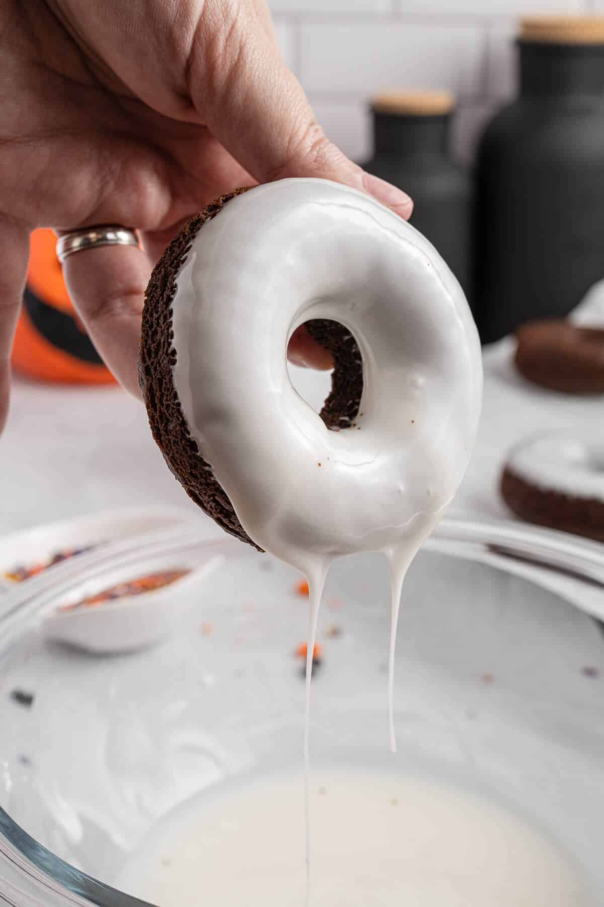 A donut dipped in a bowl of icing.