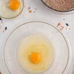 an egg mixed with oil in a glass bowl.