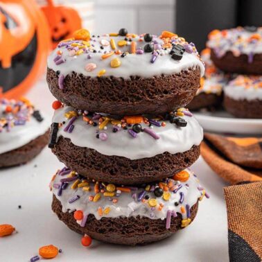 Chocolate donuts stacked on a plate.