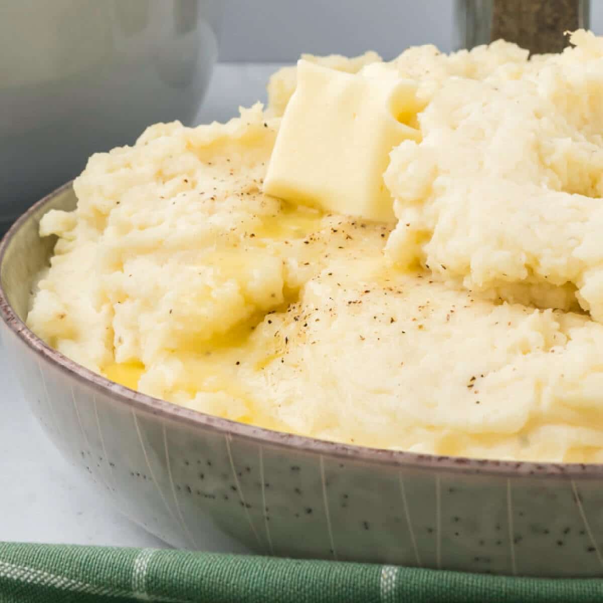 A bowl of mashed potatoes topped with a pat of butter.