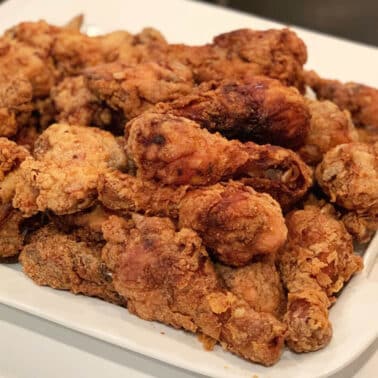 Southern fried chicken pieces on a white platter.