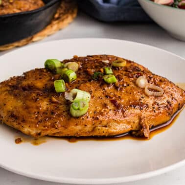A white plate with a chicken in garlic sauce.