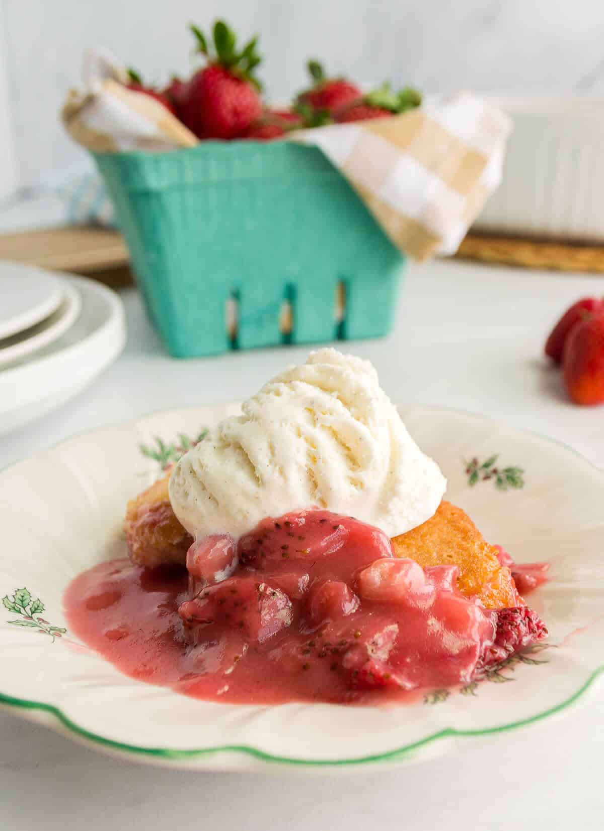 A white plate with a serving of strawberry cobbler and vanilla ice cream.