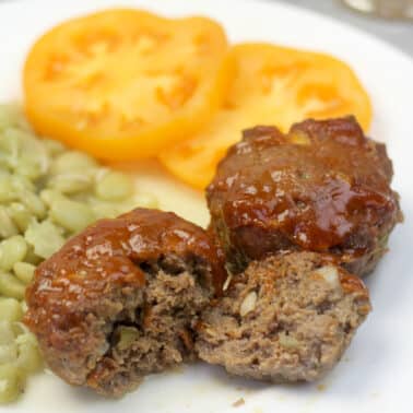 A plate with vegetables and meatloaf muffins.
