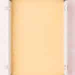 Unbaked cake batter in a rectangular metal baking pan on a pink surface.