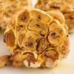 Close-up of roasted garlic bulbs, with the cloves exposed and seasoned with black pepper.