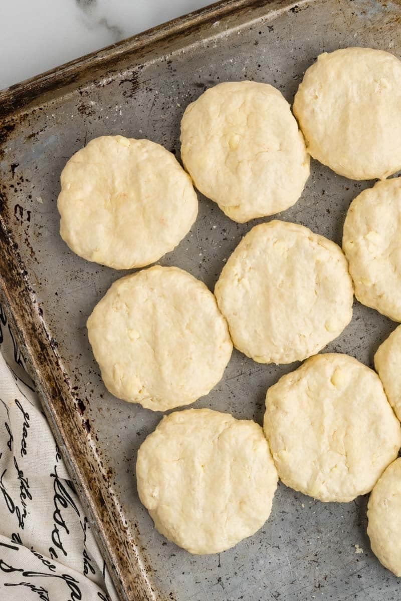 A baking sheet with unbaked, evenly spaced biscuits arranged in rows.