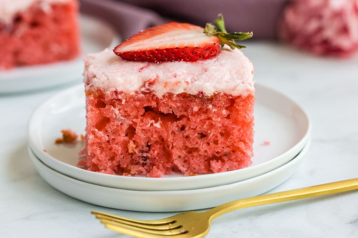 A piece of strawberry cake with a strawberry on top.