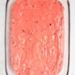 Glass baking dish filled with pink, strawberry-flavored batter, ready for baking.