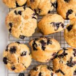 A cooling rack with freshly baked blueberry muffins, some with sugar sprinkled on top, arranged neatly.