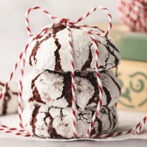 Three red crinkle cookies stacked and tied with red and white striped string.