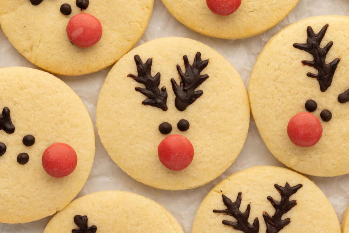 Round cookies decorated with chocolate antlers, candy eyes, and red nose to resemble reindeer faces.