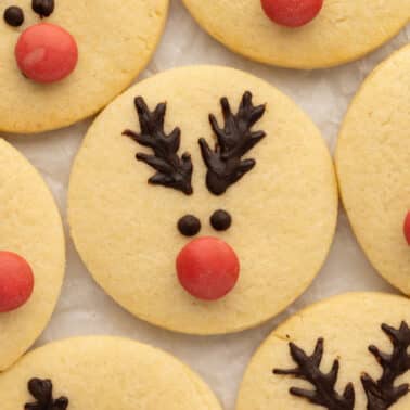 Round cookies decorated with chocolate antlers, candy eyes, and red nose to resemble reindeer faces.