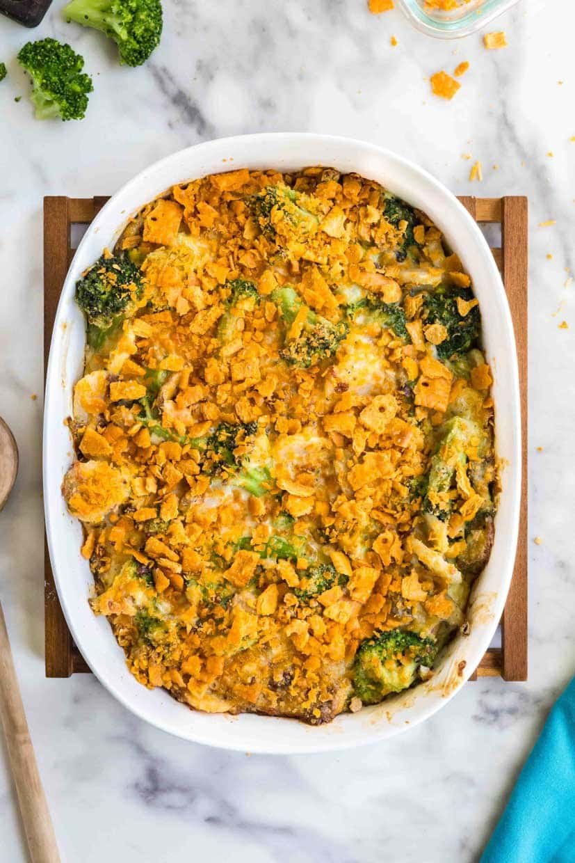 A baked broccoli casserole with a golden, crispy topping in an oval dish, placed on a marble surface.