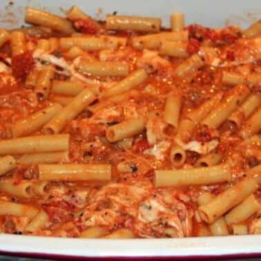 Baked ziti pasta with tomato sauce and melted cheese in a rectangular dish.